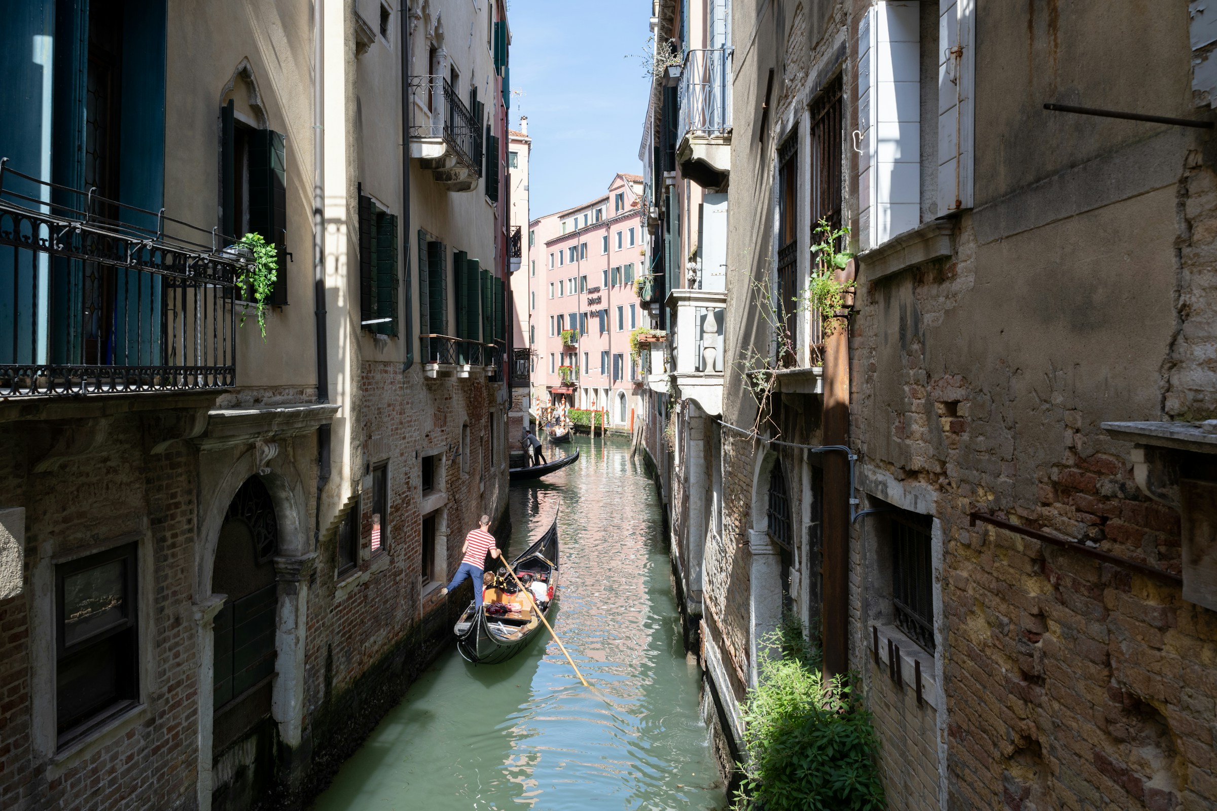 A gondola travels through a narrow venetian canal.