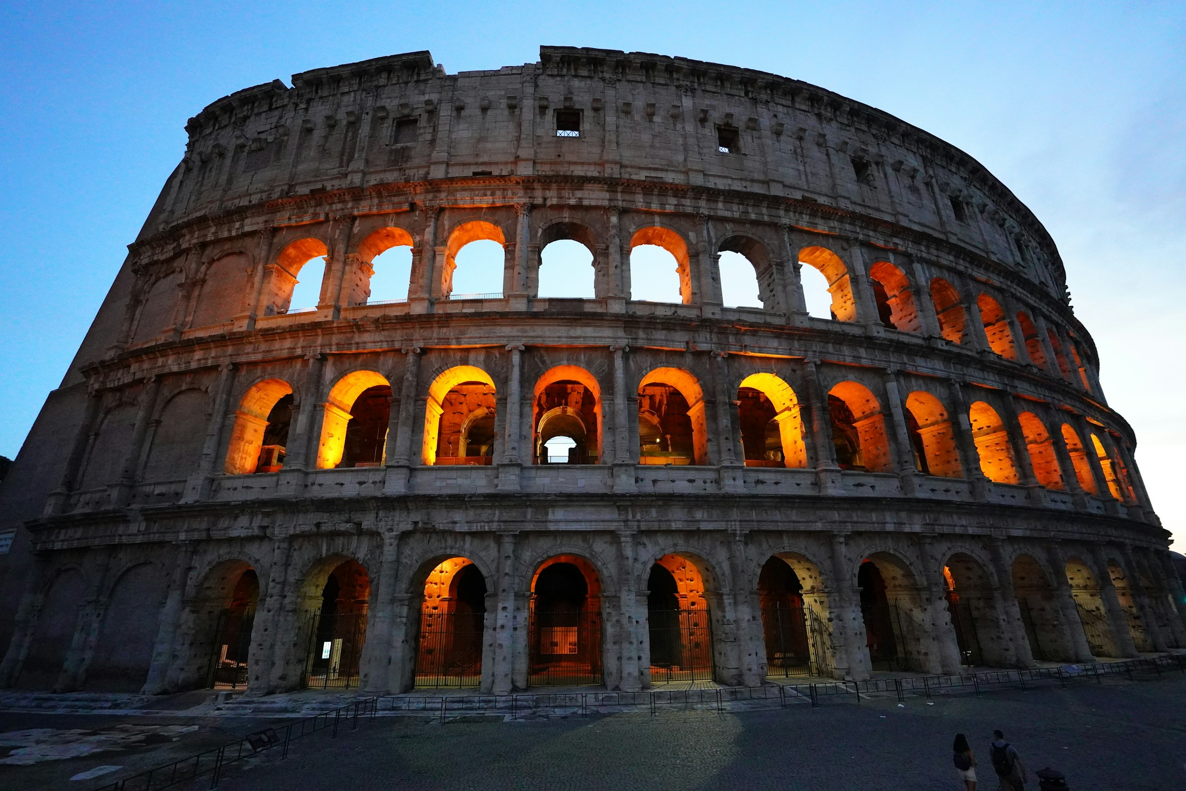 The colosseum is illuminated at dusk.