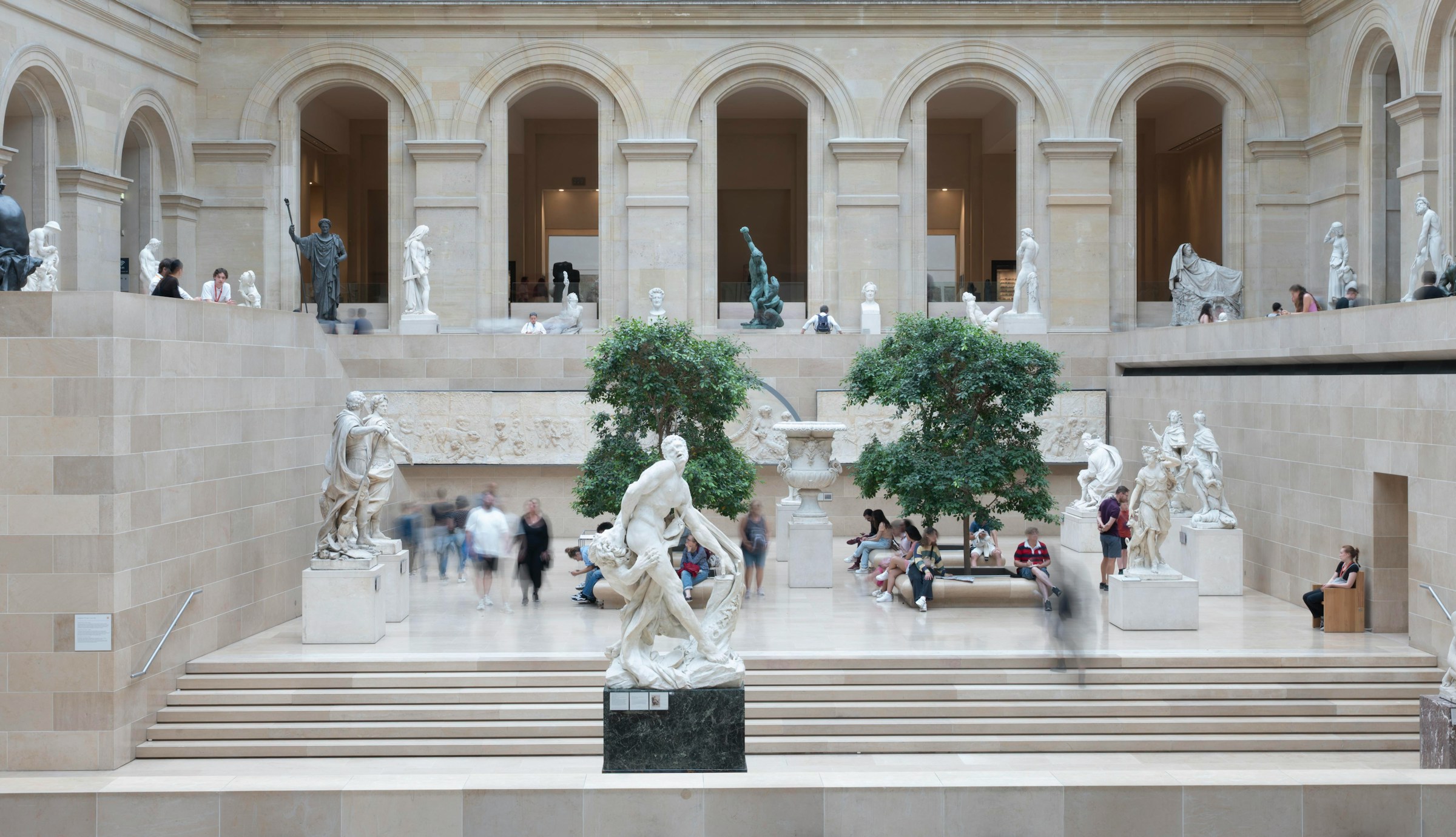 People in a grand museum with classical sculptures